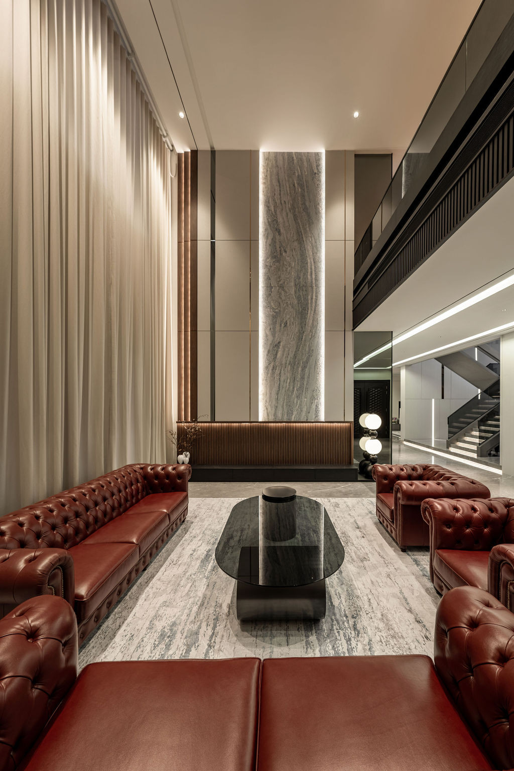 The guest entertaining lounge with double-height ceiling and rich leather seating, deliberately separated from the family areas to create distinct zones for public and private interactions