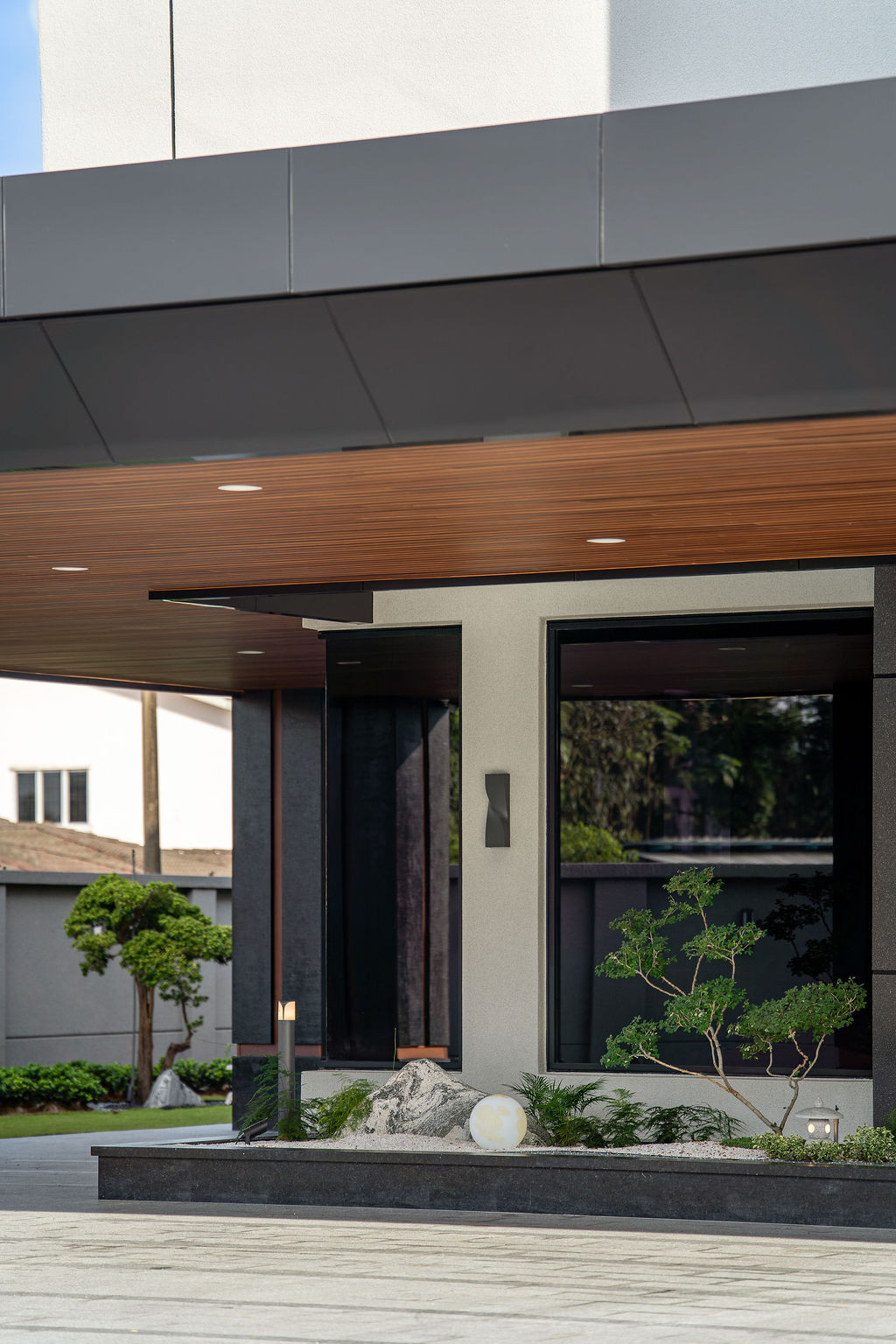 Entrance detail showing the WPC ceiling material and natural stone combination, representing the textural continuity and weather resistance prioritized in the design
