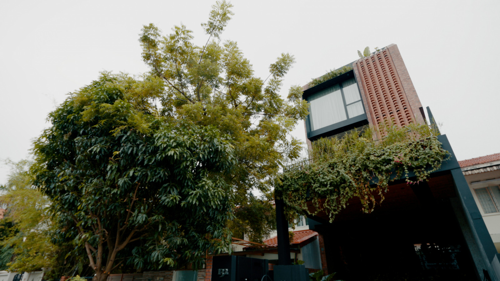 Designed by Edmund Ng Architects, the home’s facade features a striking mix of brick, breeze blocks and cascading greenery