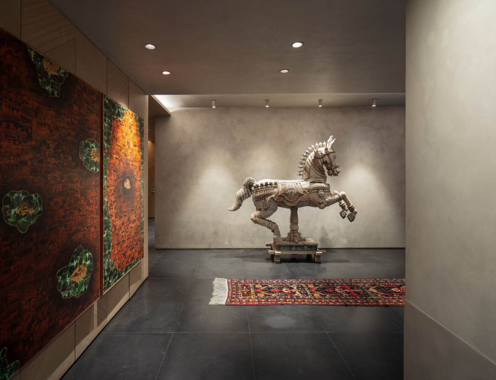 A traditional carved horse sculpture anchors the entrance hall, positioned against grey walls that complement the neutral palette