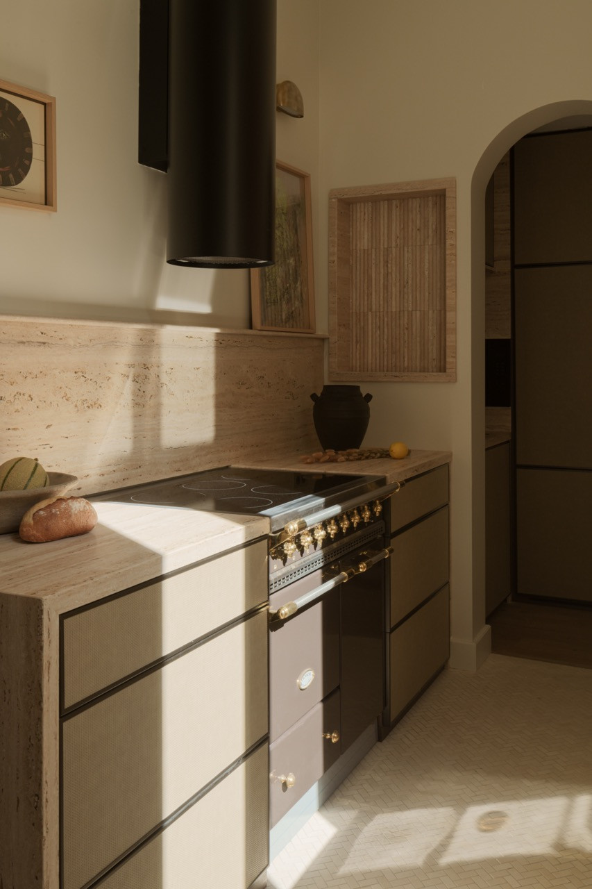 The kitchen showcases unfilled and backlit light travertine with grey stripes, which Ashby notes she loves “how it looks in the kitchen when it’s unfilled and backlit”