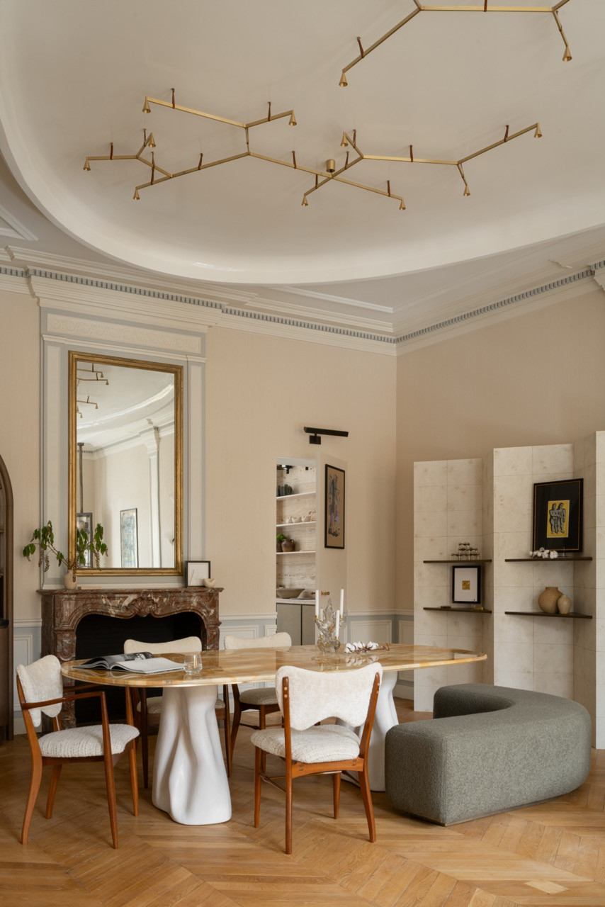 The dining area features a red marble fireplace inherited from the past, alongside a branch-like ceiling installation that Ashby says reminds her of a sky filled with shining constellations, referencing the curved ceilings of Parisian palaces
