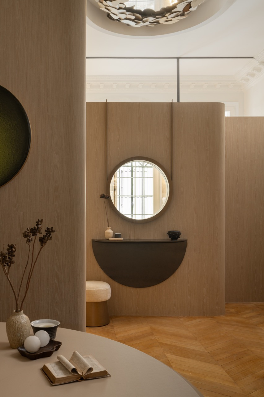 The bathroom’s curved basin and circular window demonstrate the apartment’s emphasis on flowing, organic forms within the 1911 Late Haussmann building