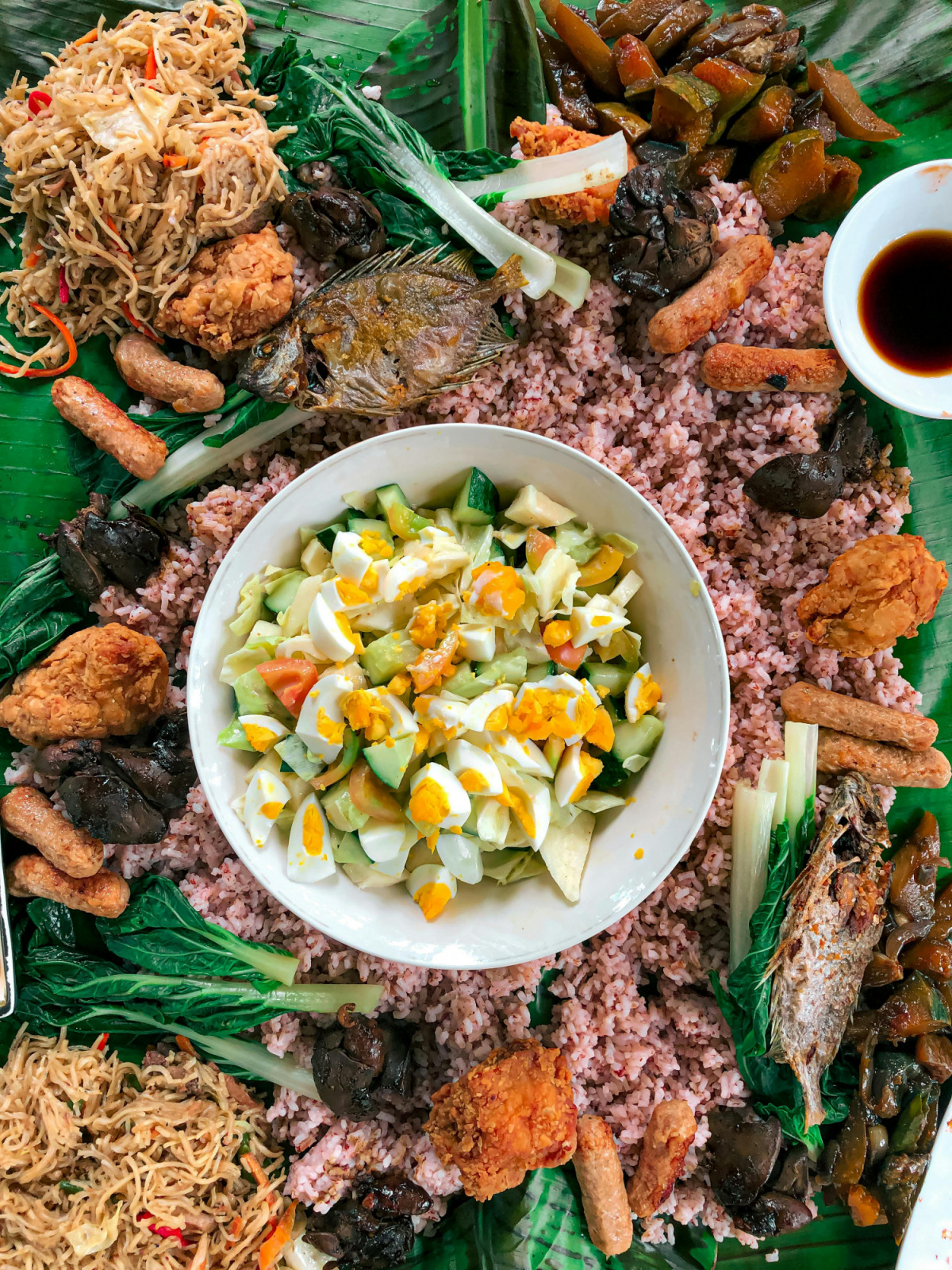 A Filipino boodle fight laid out on banana leaves with rice, pork and seafood