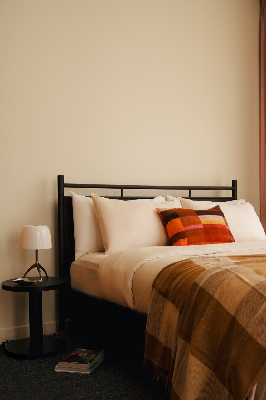 The bedroom maintains the cooler colour palette that Ee used for private spaces, with warm timber flooring providing continuity throughout the flat