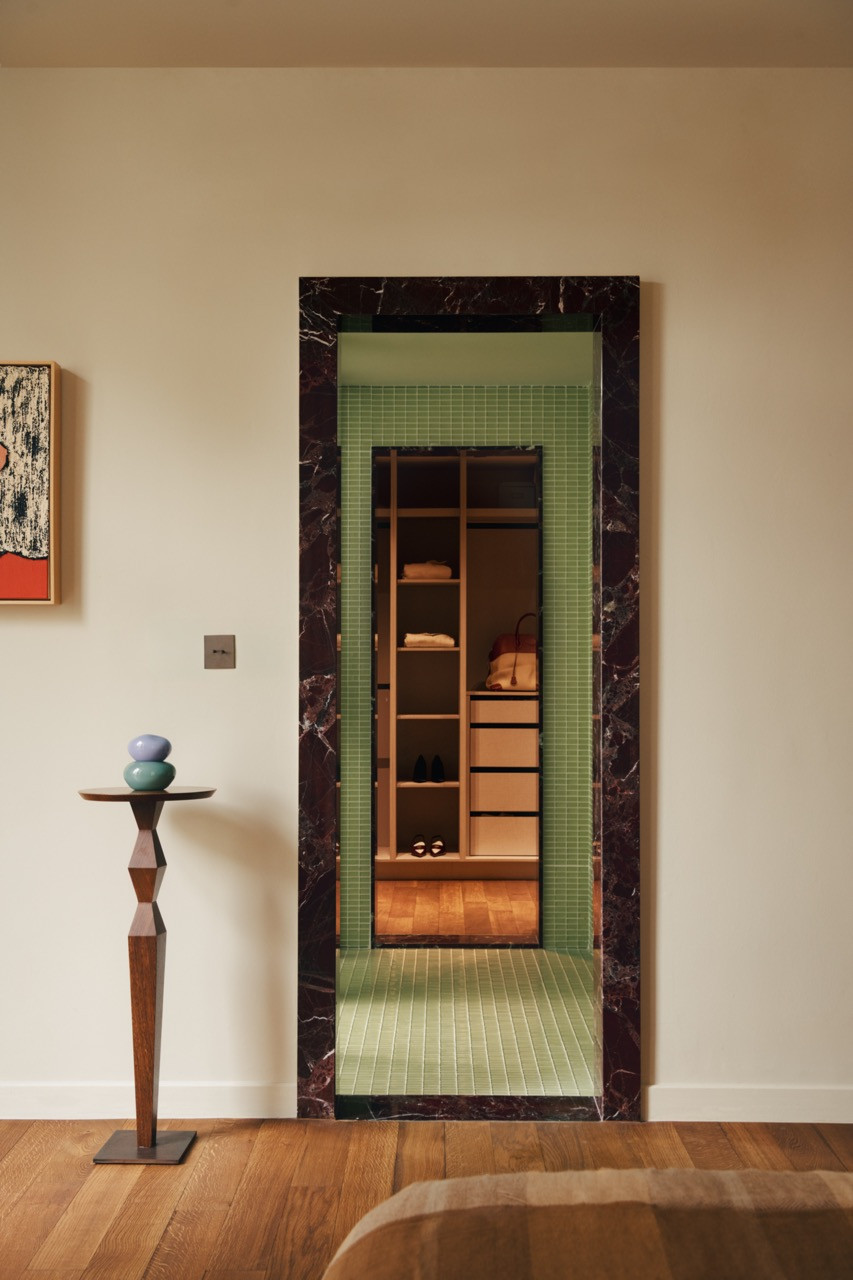 The doorway from the living area reveals the wardrobe space beyond, framed by the same burgundy marble that appears throughout, creating visual continuity between rooms