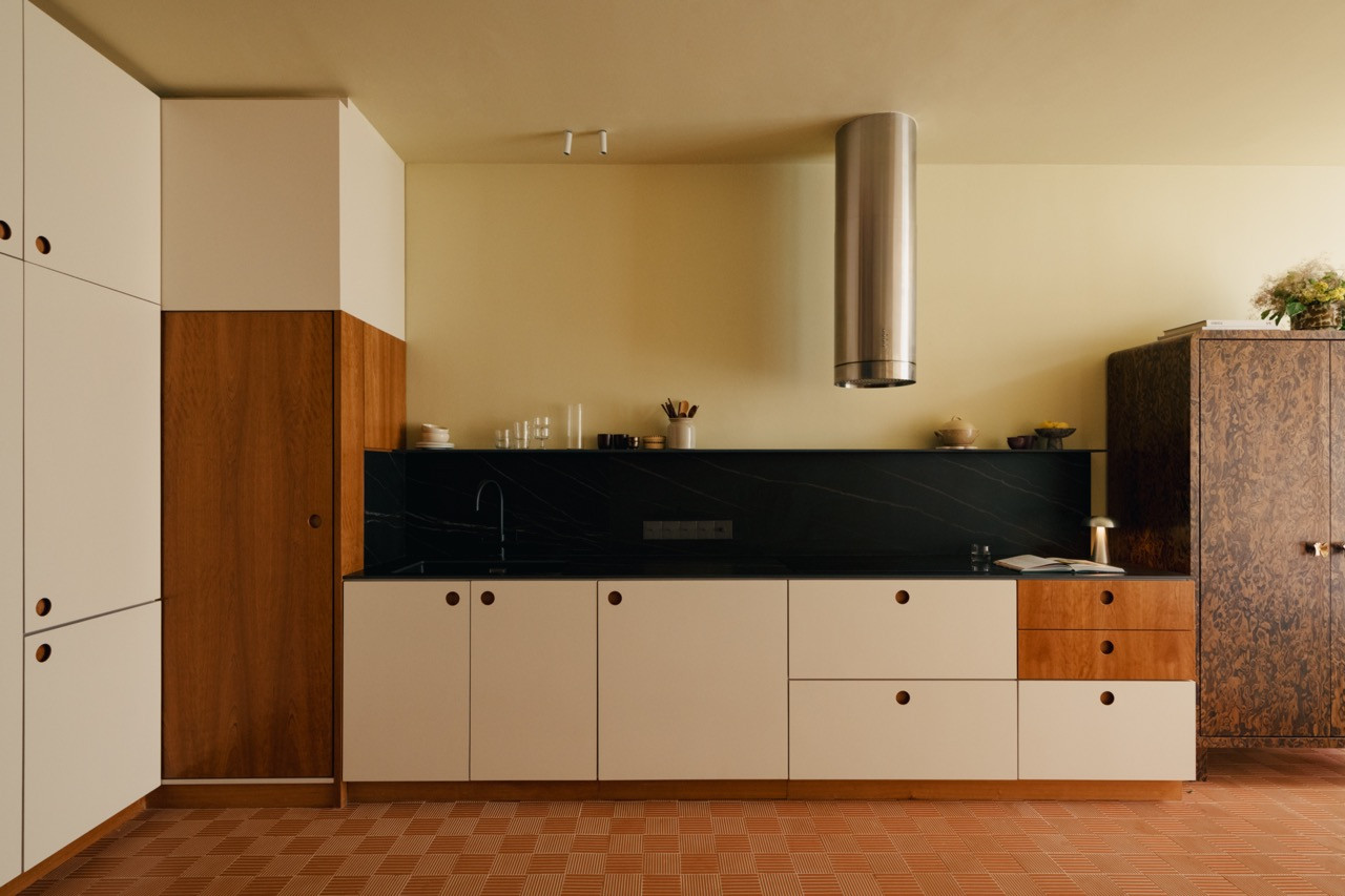 The kitchen showcases the warm material palette with cherry wood veneer cabinetry paired with white units, set against dark sintered stone surfaces and terracotta Mutina tiles