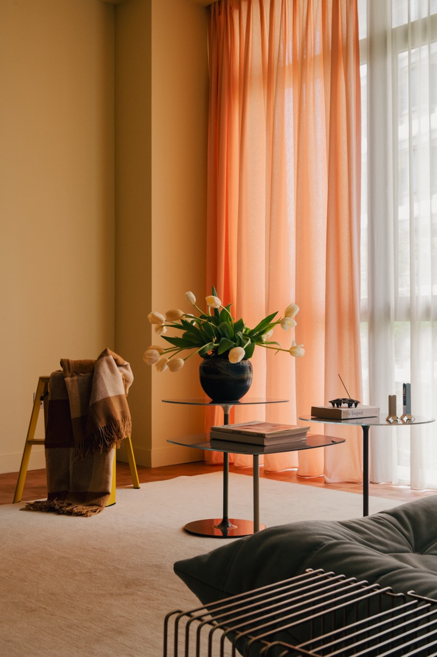 The living area features a Kartell Thierry coffee table cluster and Montana Furniture modular side table by Verner Panton, complemented by fresh tulips and warm evening light