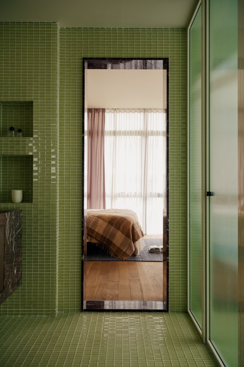A view through to the bedroom shows the cooler tones used in private spaces, contrasting with the warm palette of the public areas