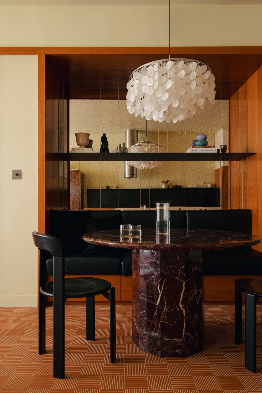 The dining area features Ee’s custom round marble table with faceted legs, paired with the black Rey dining chairs and illuminated by the Verner Panton FUN pendant lamp