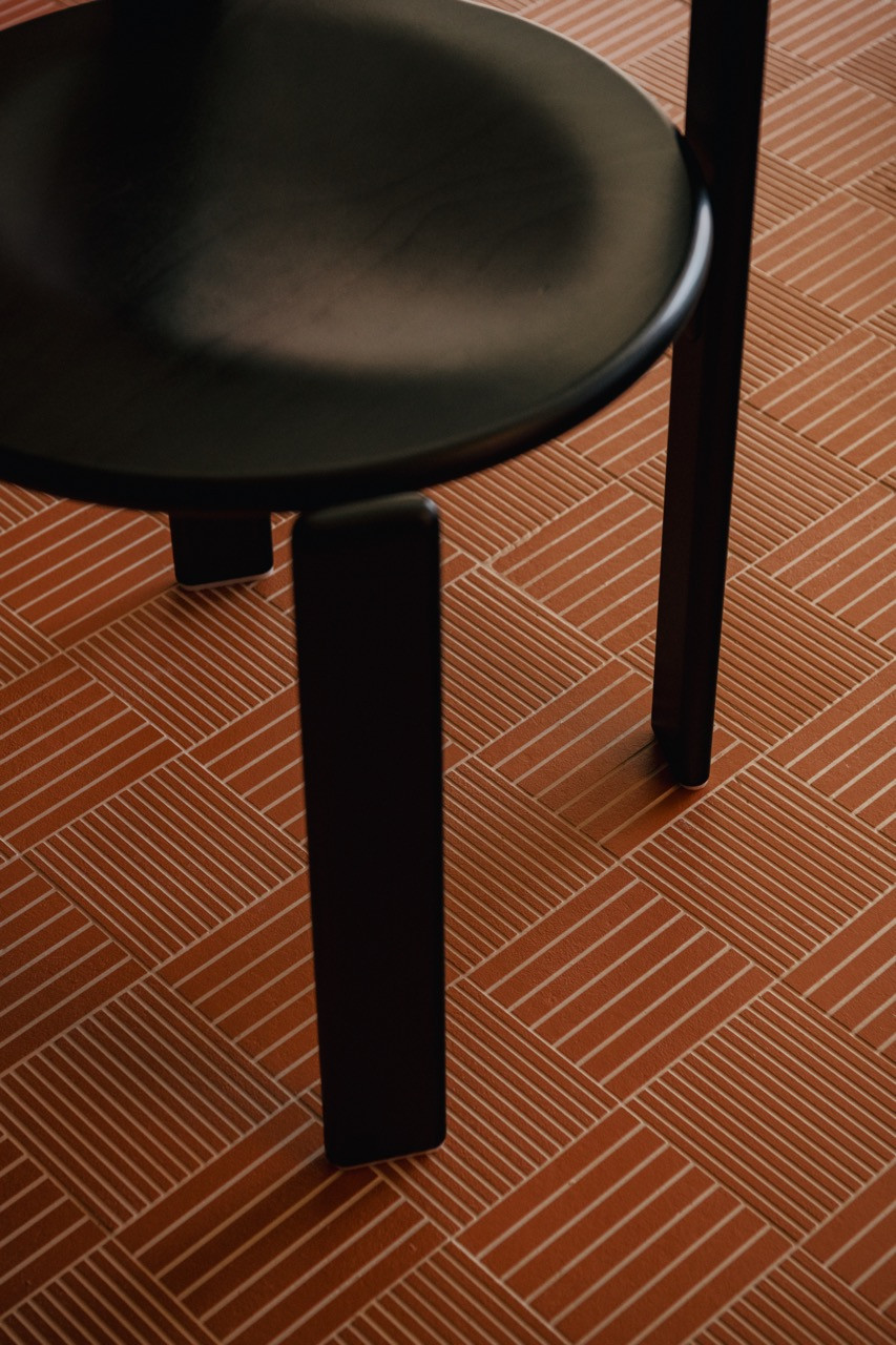 A close-up detail of the Rey dining chairs by Bruno Rey, showing how they work with the terracotta tile grid pattern that informed all other material choices throughout the flat