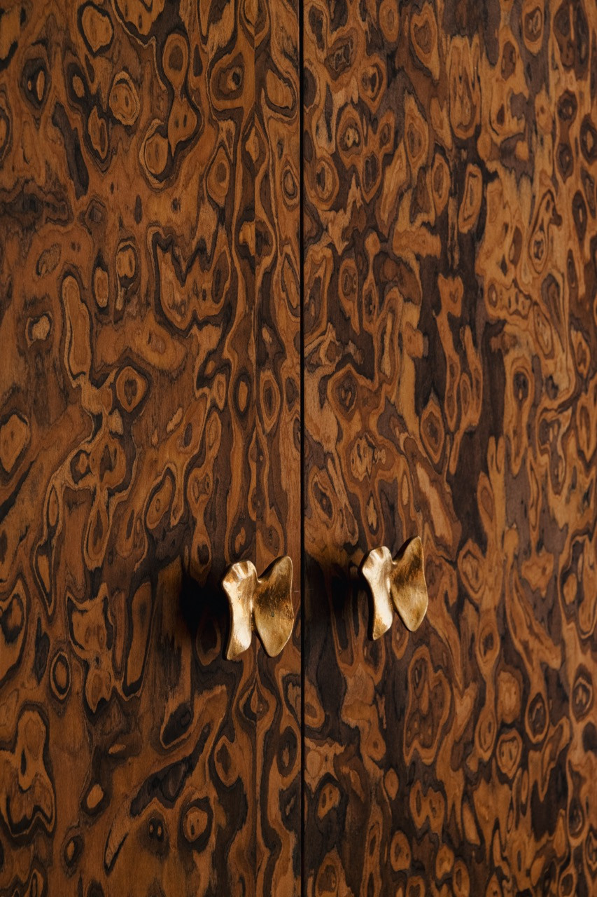 A detail of the California burl veneer showing the intricate wood grain pattern, finished with bronze handles from a Belgian maker to complete this standout piece