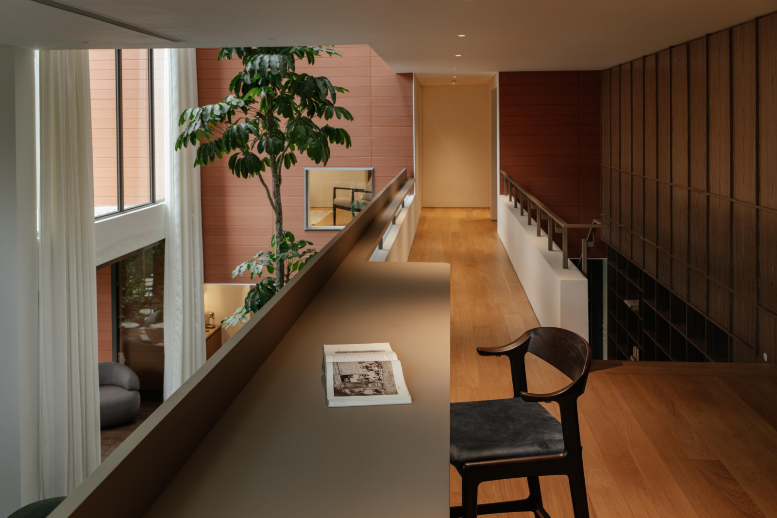 The upper-level hallway leading to the bedrooms continues the overall warm palette, augmented by glimpses of lush indoor foliage