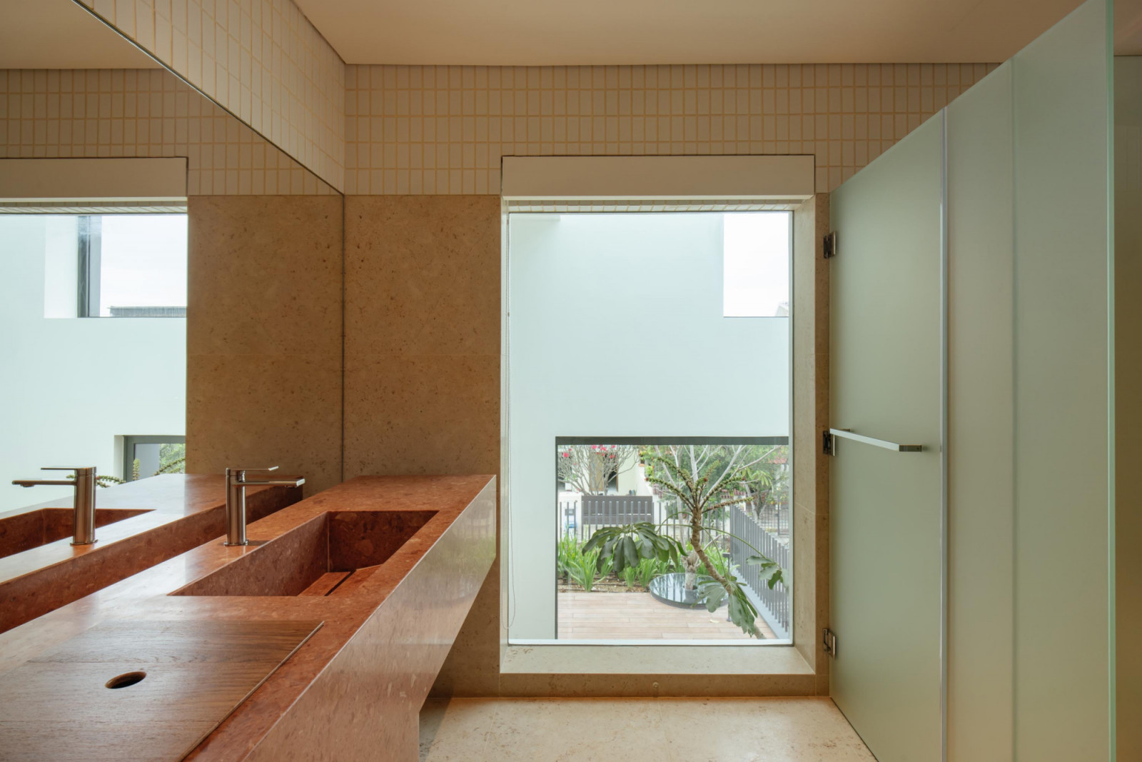 This bathroom’s vanity area is naturally lit by a large window that of fers a view to the garden outside
