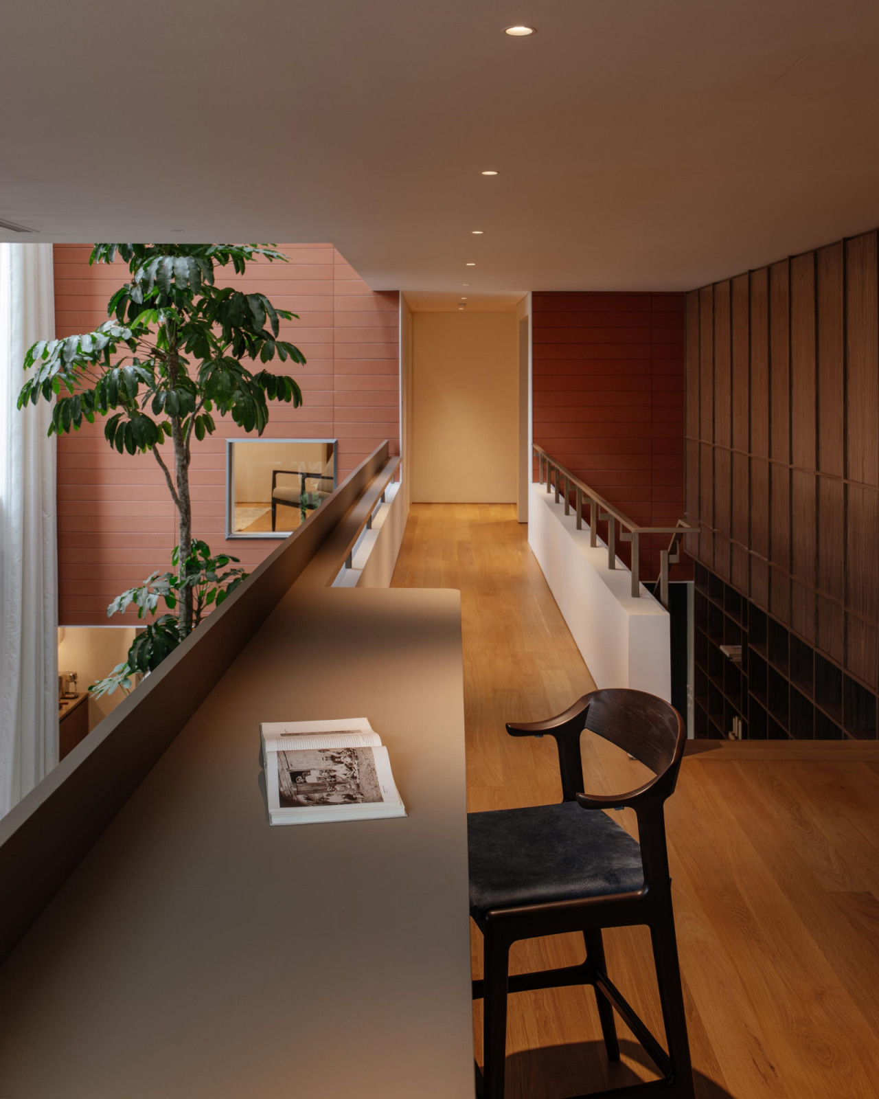 The upper-level hallway leading to the bedrooms continues the overall warm palette, augmented by glimpses of lush indoor foliage