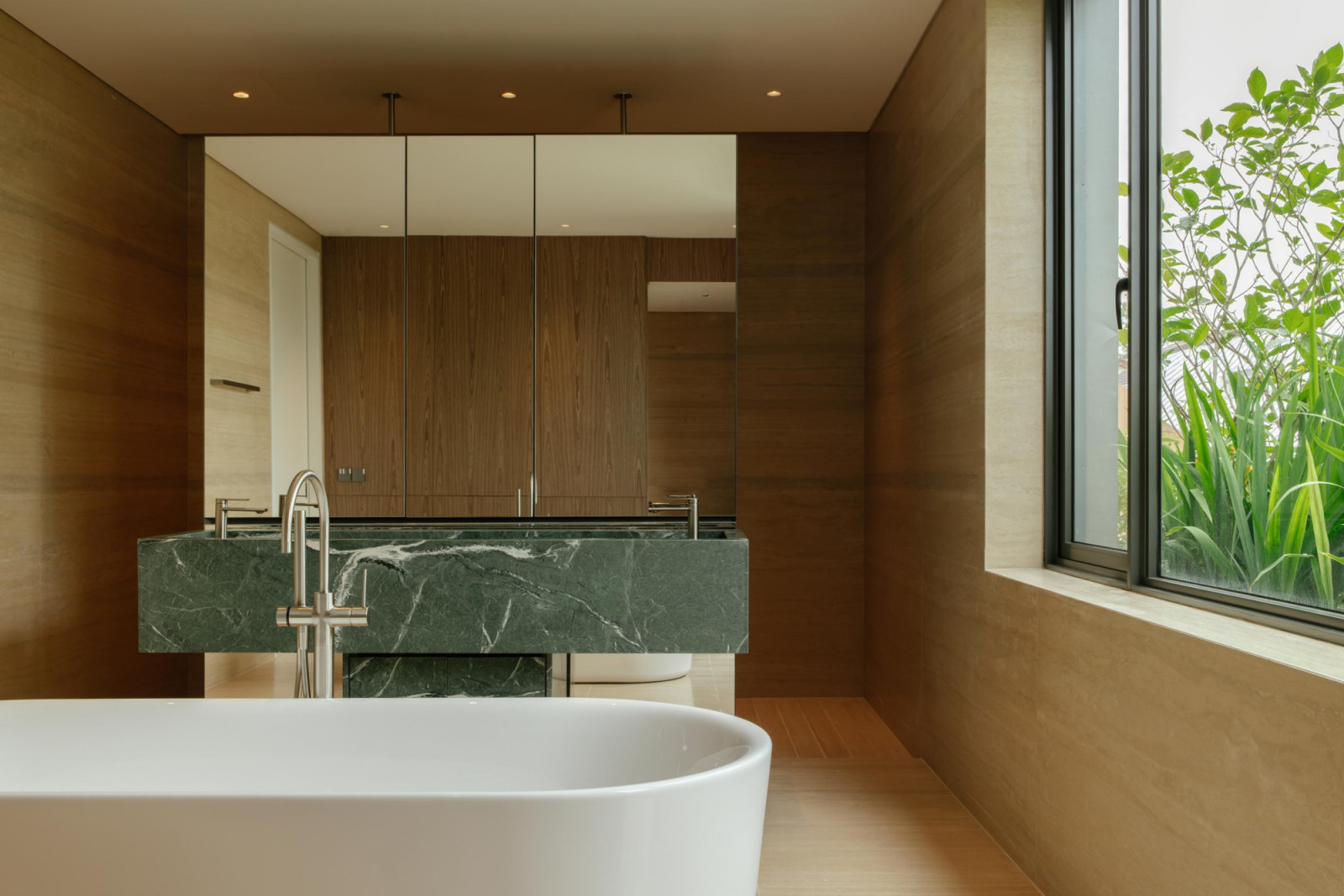 Green marble adds a fresh accent to the bathroom, with a generously sized mirrored cabinet doubling the perception of space here