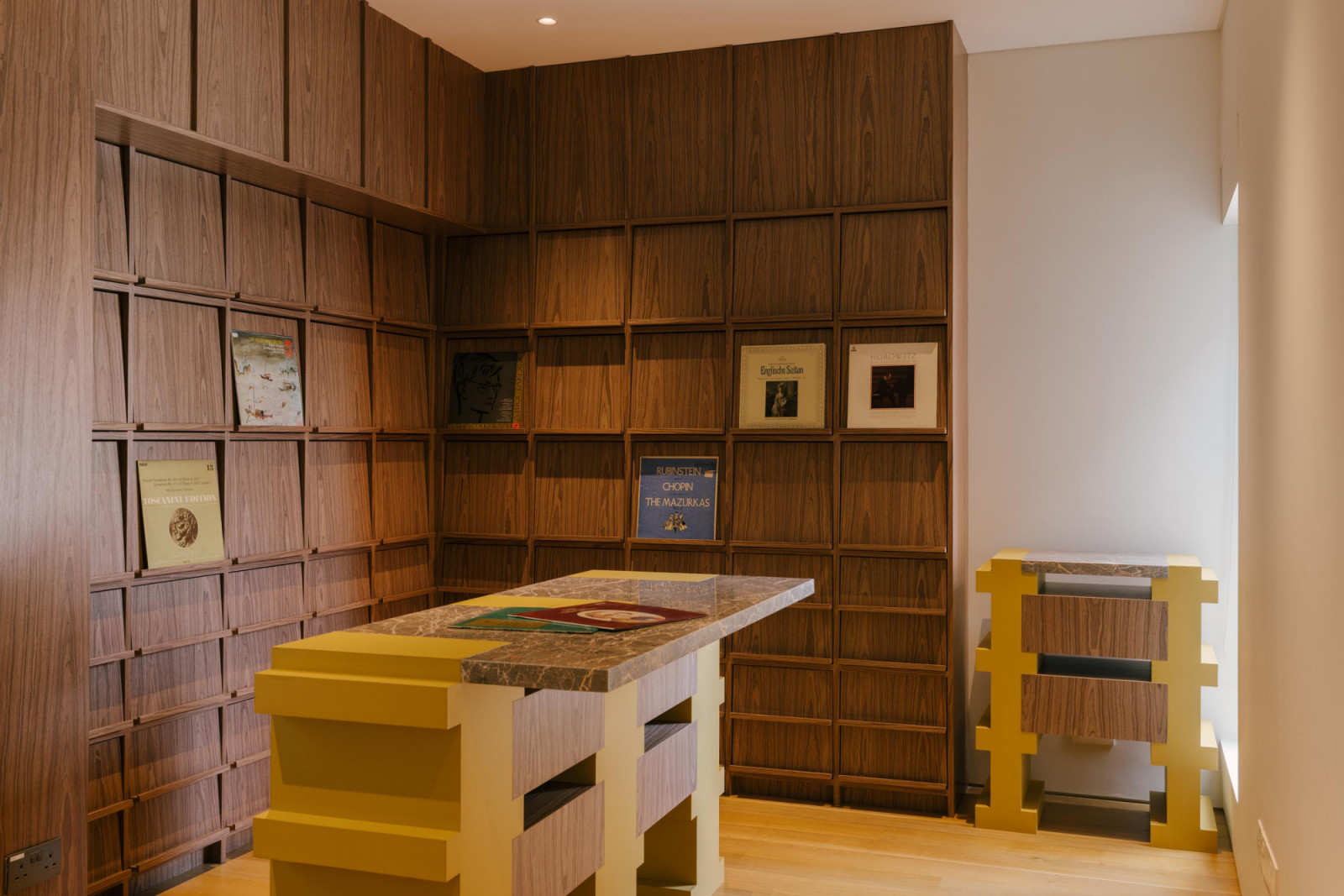 The AV library’s custom cabinetry is accented with yellow paint and topped with marble