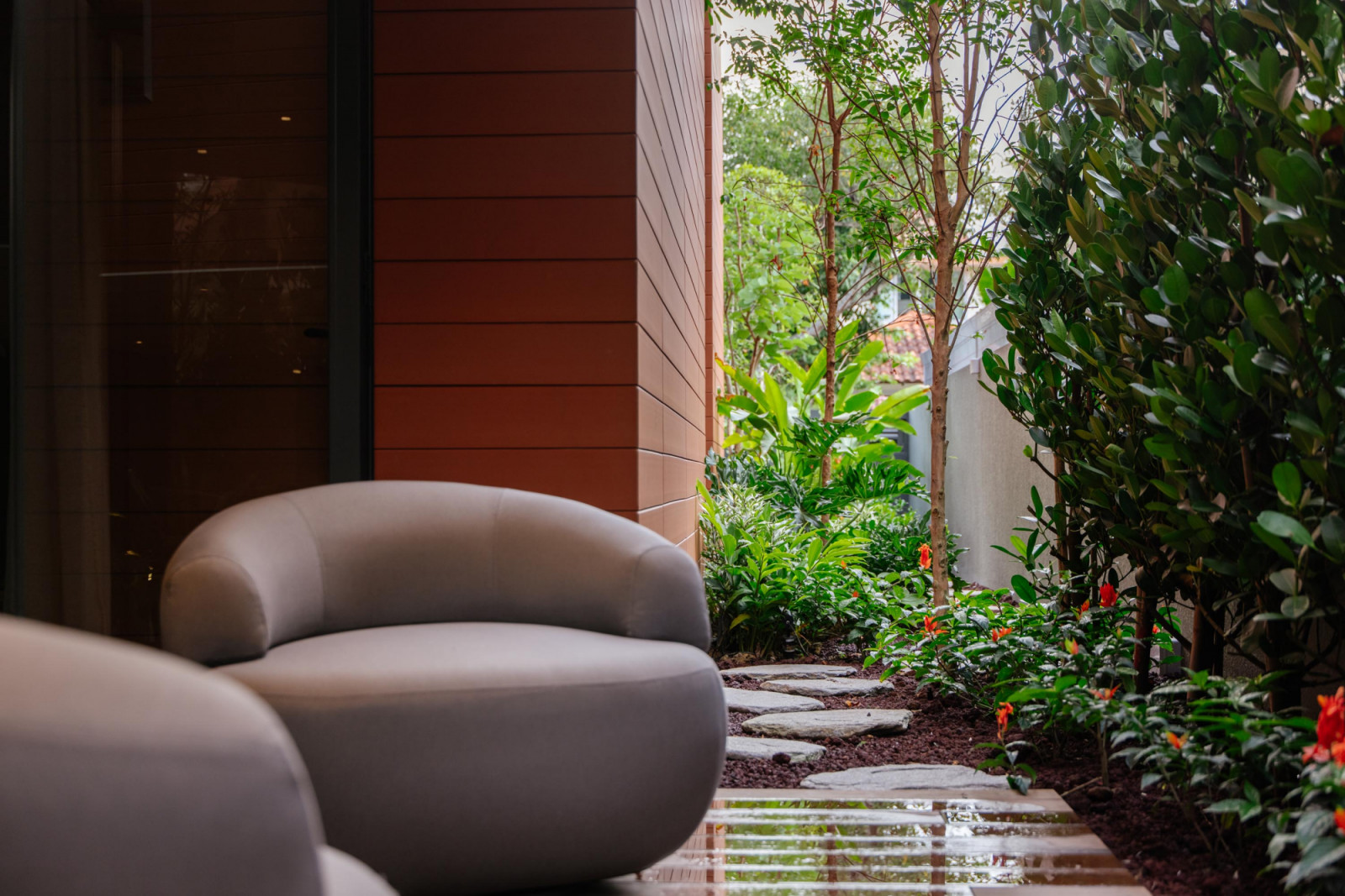A pocket terrace edged with lush planting offers a quiet outdoor retreat, where the terracotta cladding extends the warmth of the interior into the garden