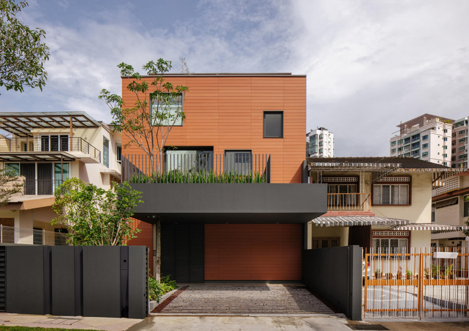 The street-facing façade of the semi-detached home presents as a clean-lined two-storey volume clad in warm terracotta