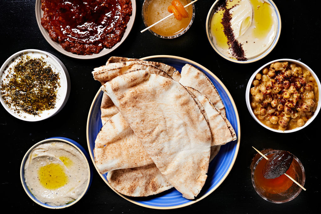 WASHINGTON, DC - FEBRUARY 6: Pita with spreads (clockwise from bottom left) baba ganoush, labneh, muhammara, a Sour cocktail, hummus, balila, and a Neat cocktail at Yasmine located inside Union Market photographed in Washington, DC on February 6, 2023. TTDI (Photo by Deb Lindsey for The Washington Post via Getty Images).