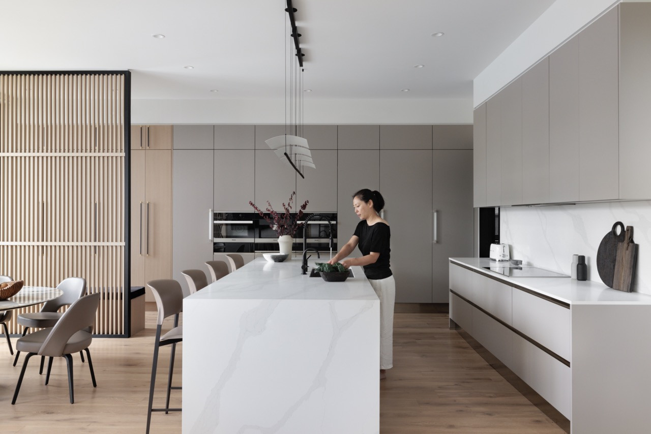 The open kitchen and dining area show how large sliding glass doors create connectivity between interior and exterior spaces, fundamental to West Coast living principles, while accommodating the family’s needs