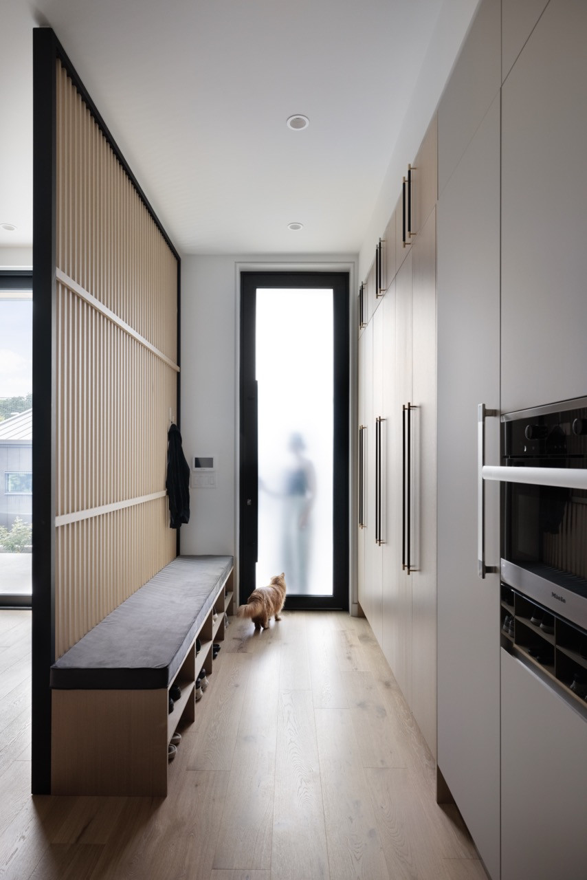 A mudroom area showcases the slatted wood panels that appear throughout the house, providing practical storage while maintaining the visual connection to traditional Chinese design elements