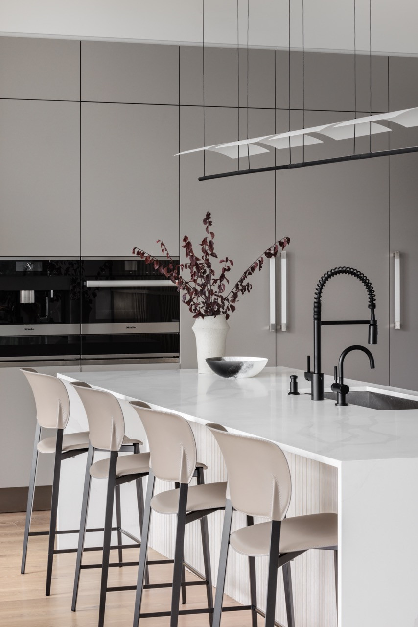 The kitchen features Arclinea cabinetry and Miele appliances, with Desalto Ply 729 stools positioned along the white countertop island, which serves as both a workspace and a gathering point