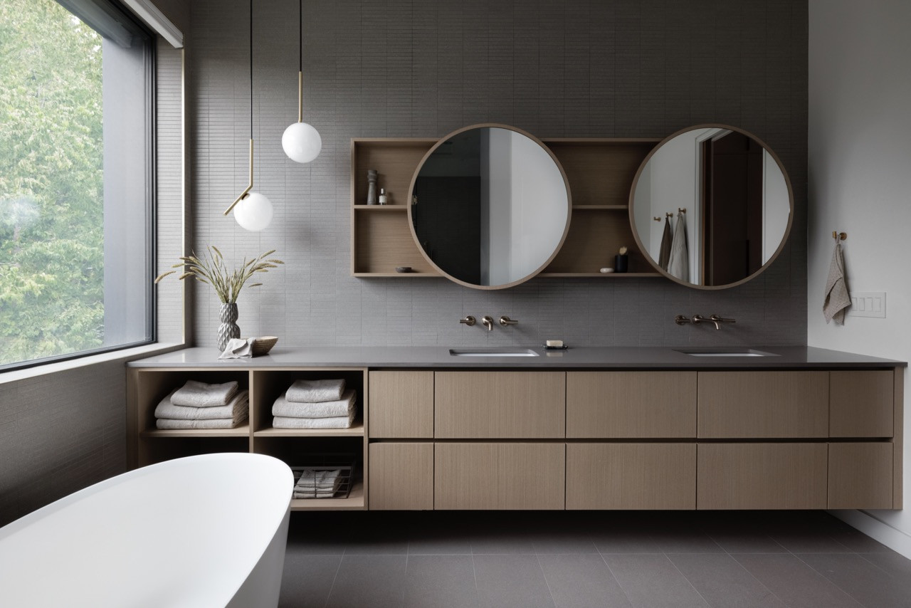 The primary bathroom's double vanity design incorporates both practical storage and the geometric precision characteristic of contemporary design, with custom wood cabinetry and integrated lighting
