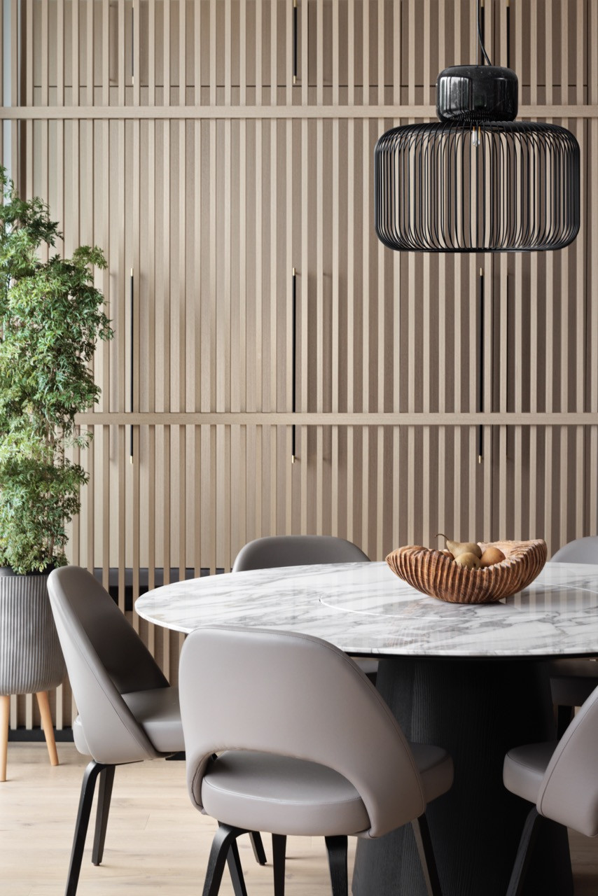 The dining area features the Porro Materic table paired with Knoll Saarinen chairs, set against the signature wood slatted wall that reinterprets the traditional Chinese “ping feng" room divider