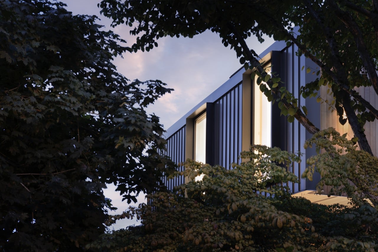 The cantilevered gable form extends over the main level, creating a protective cover for the recessed entry patio while establishing the home's contemporary architectural identity