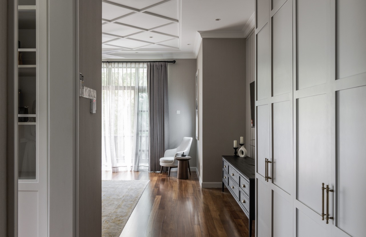 The dressing room employs floor-to-ceiling storage with glass-fronted cabinetry and coffered ceiling details