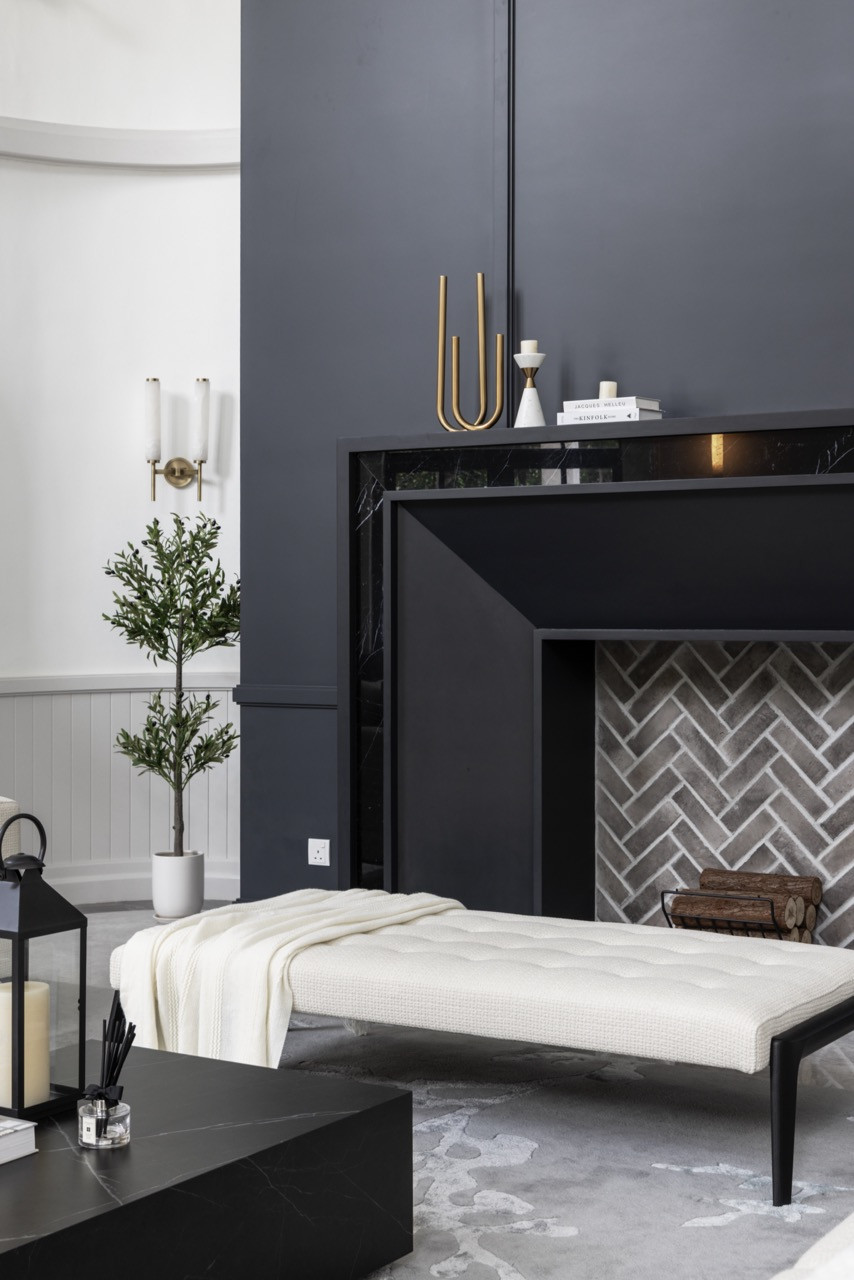 The bold fireplace clad in dark marble with dramatic veining becomes the true focal point of the living area while the herringbone tile pattern within the fireplace opening adds textural interest