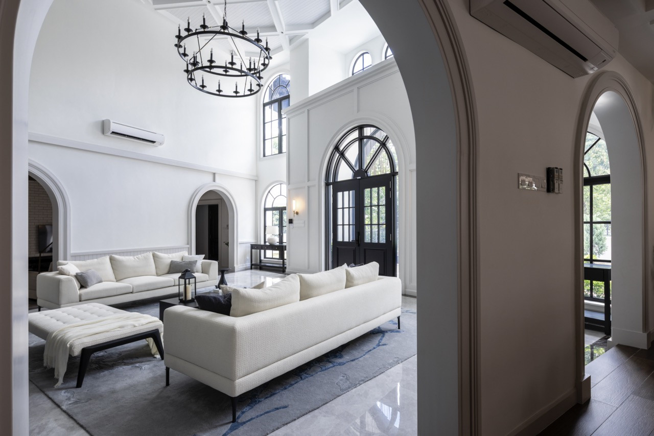 The double-height living space features neutral furnishings beneath cathedral-like proportions