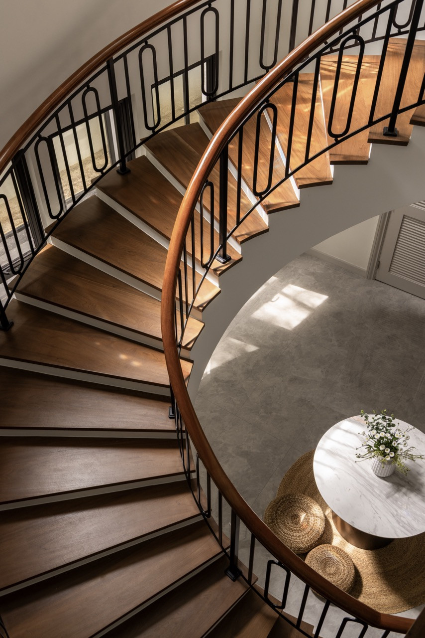 The sculptural spiral staircase with rich wooden treads and sleek black balustrade