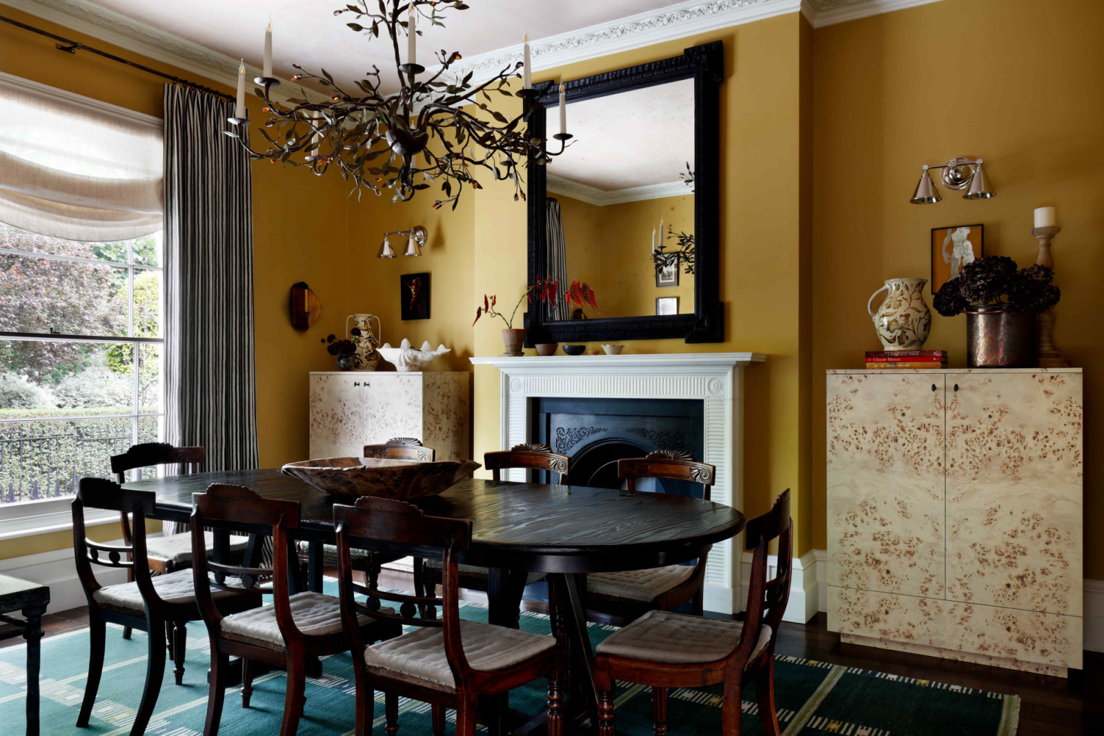 Set against a palette of sunny yellow and dark green, custom-made burr wood cabinets flank the fireplace