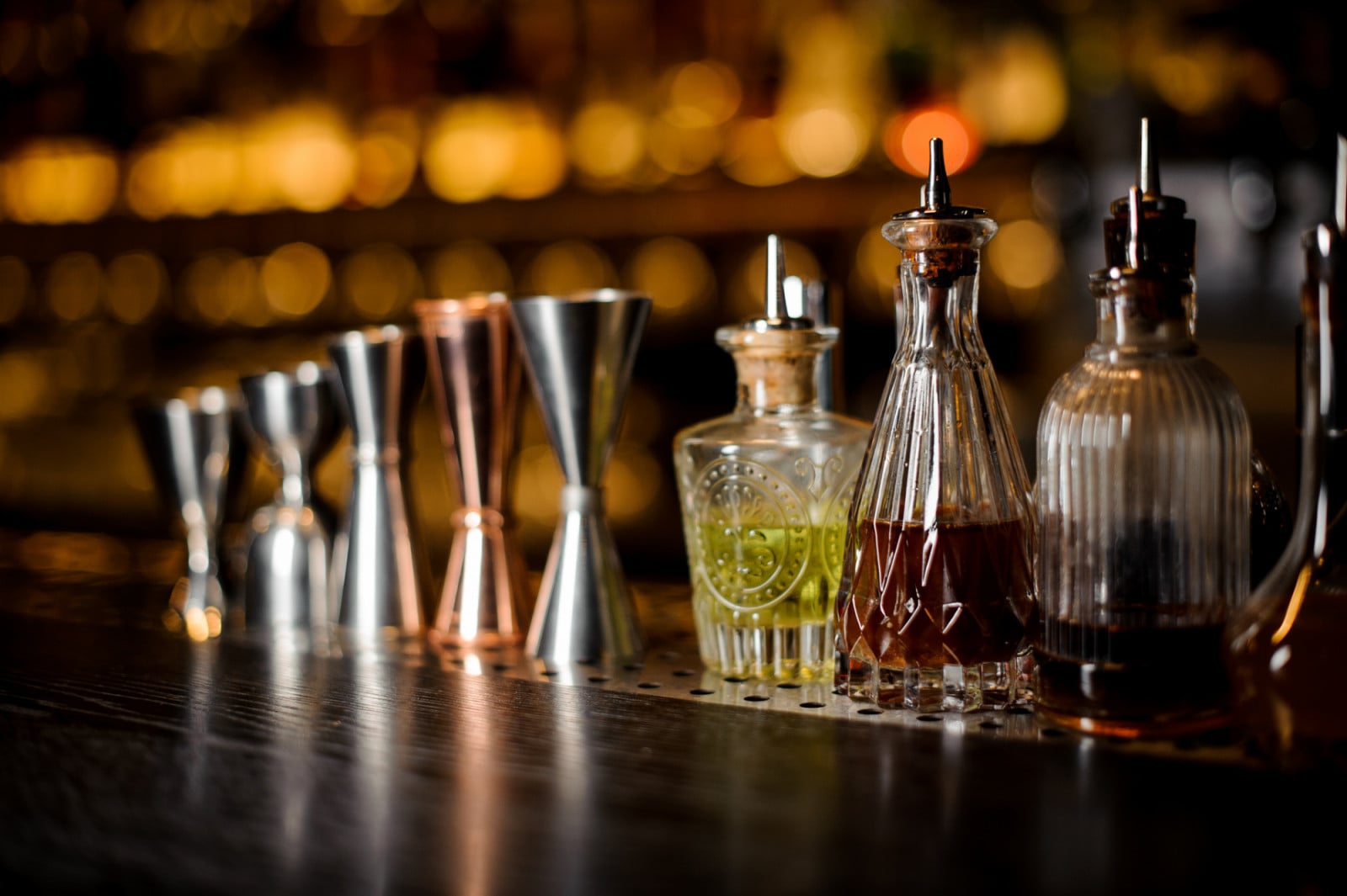 Set of professional barman tools including jiggers and little bottles with liquor and bitters of different colors