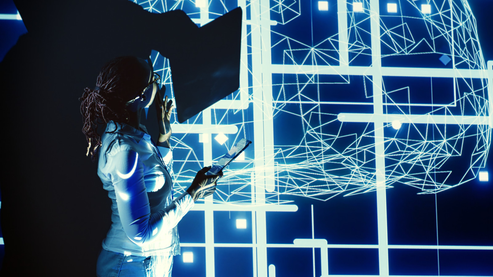 System administrator programming in AI server farm housing advanced equipment used for machine learning training. Programmer running code on tablet to update artificial intelligence rigs