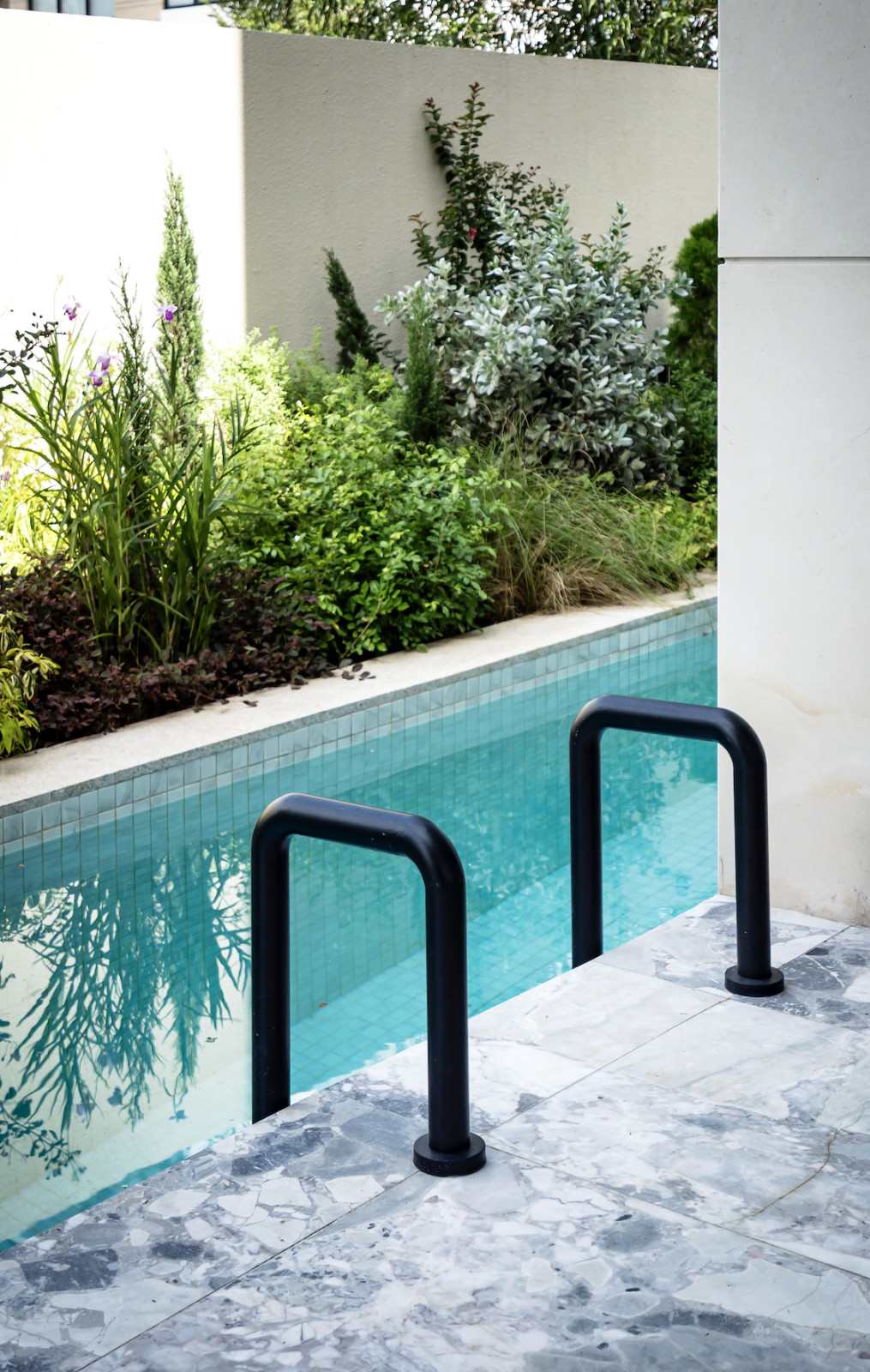 The beautifully modern curved pool handles provide contrast to the garden