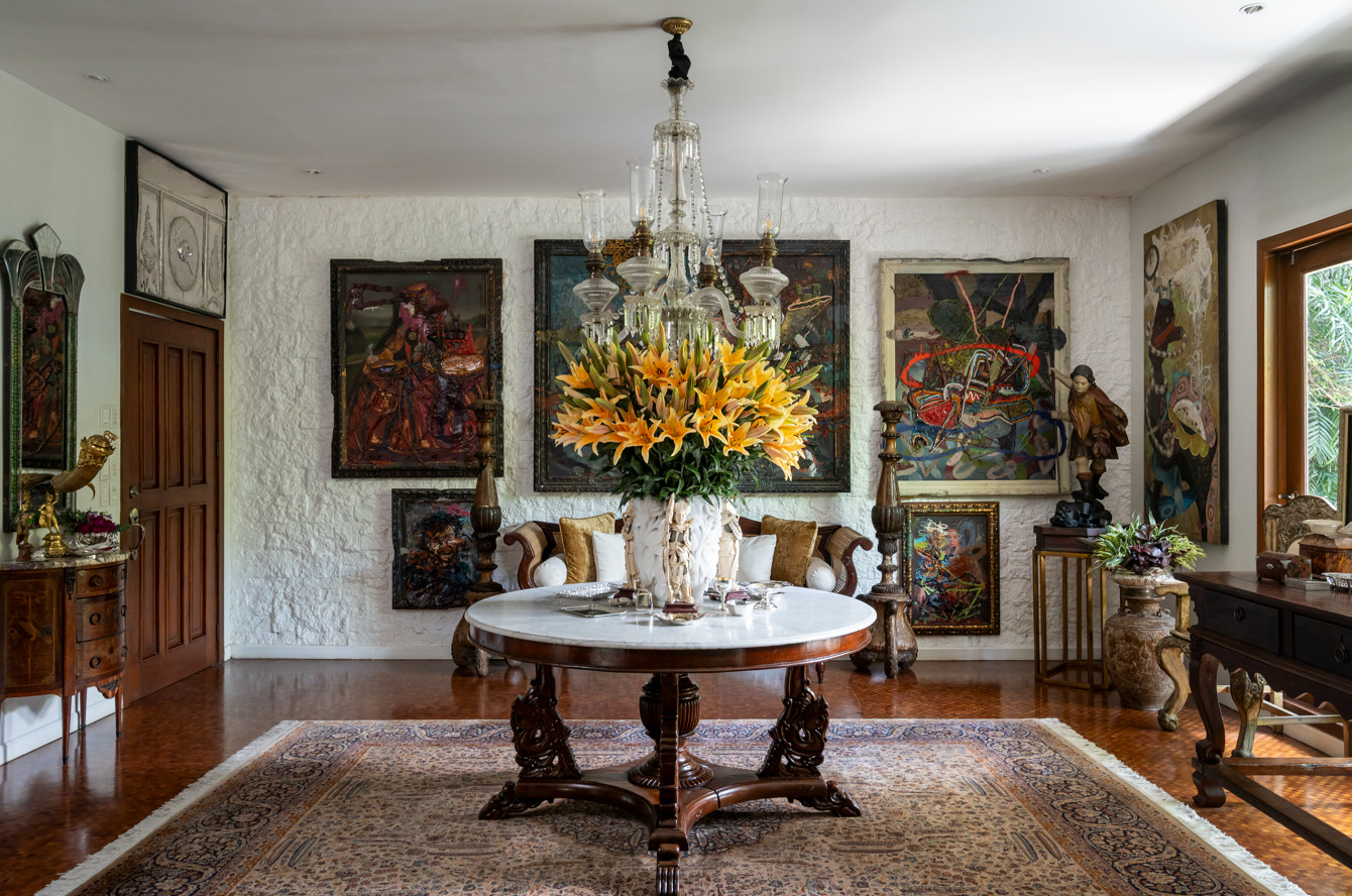 Foyer with an antique Baccarat chandelier set against contemporary Jigger Cruz paintings. Antique silver and ivory pieces adorn the tabletop (Photo: Toto Labrador)