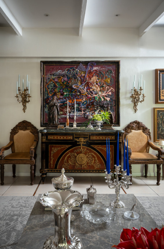 An antique French commode is paired with 18th-century Filipino bishop’s chairs and santos, contrasted by a bold contemporary artwork by Jigger Cruz (Photo: Toto Labrador)