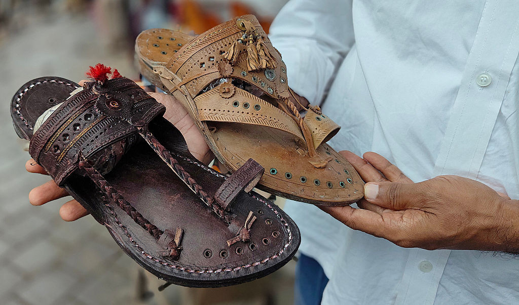 MUMBAI, MAHARASHTRA, INDIA - 2025/07/04: A shopkeeper shows pair of Kolhapuri chappals (handcrafted Indian sandal) displayed for sale at a street side shop. Italian luxury fashion brand Prada which launched its 'Toe Ring Sandals' is accused of copying the design inspired by Kolhapuri chappals (handcrafted Indian sandal) without giving due credit to indigenous artisans who created them in Kolhapur district of Maharashtra centuries ago. A Public Interest Litigation (PIL) has been filed in Bombay High Court se