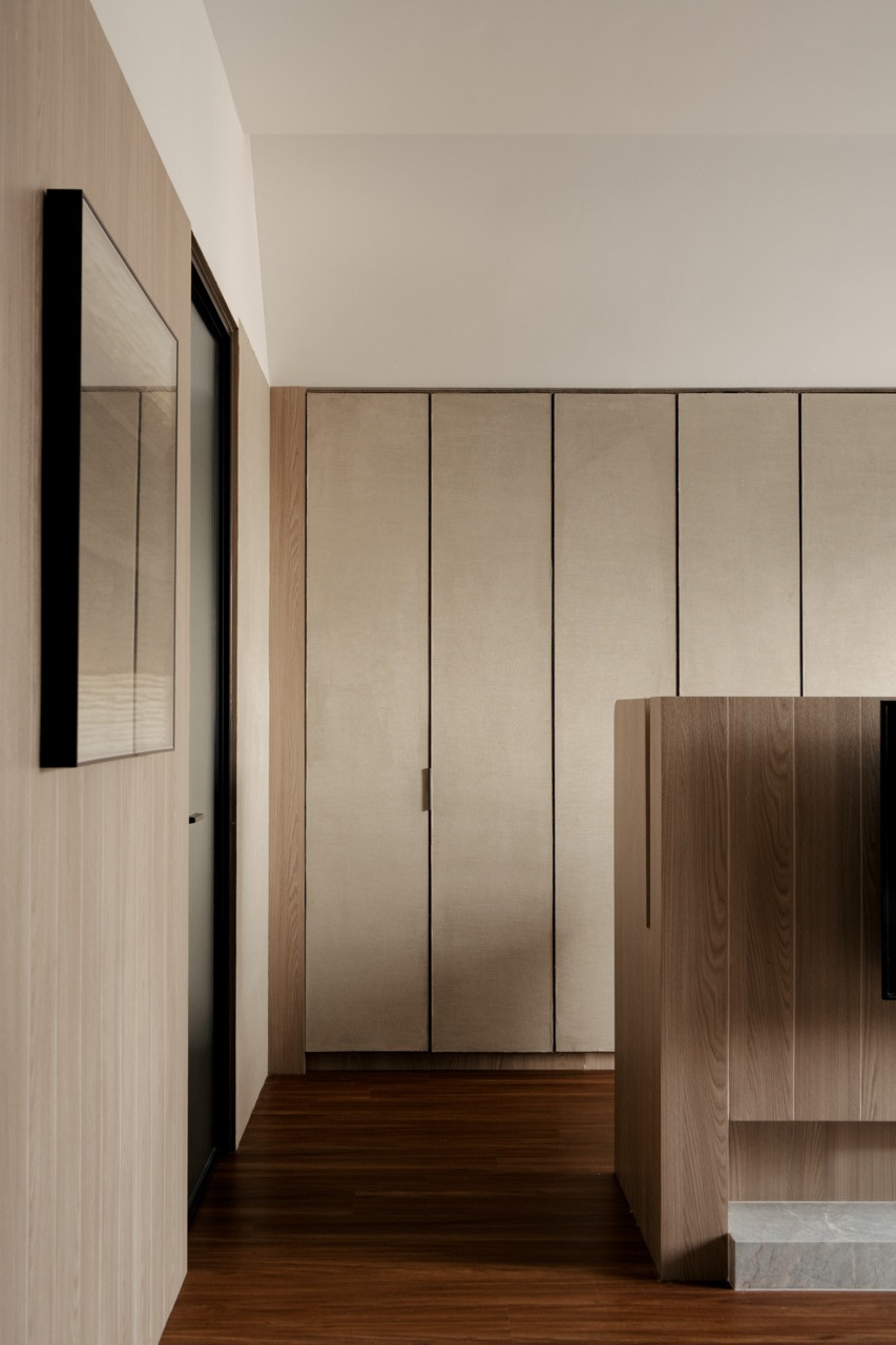 Built-in storage maximises space efficiency in the corridor, featuring floor-to-ceiling cabinets in neutral tones that complement the warm wood flooring