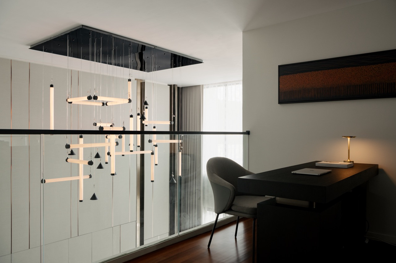 The upper-level office space features a dramatic lighting installation that serves as both functional workspace illumination and architectural sculpture