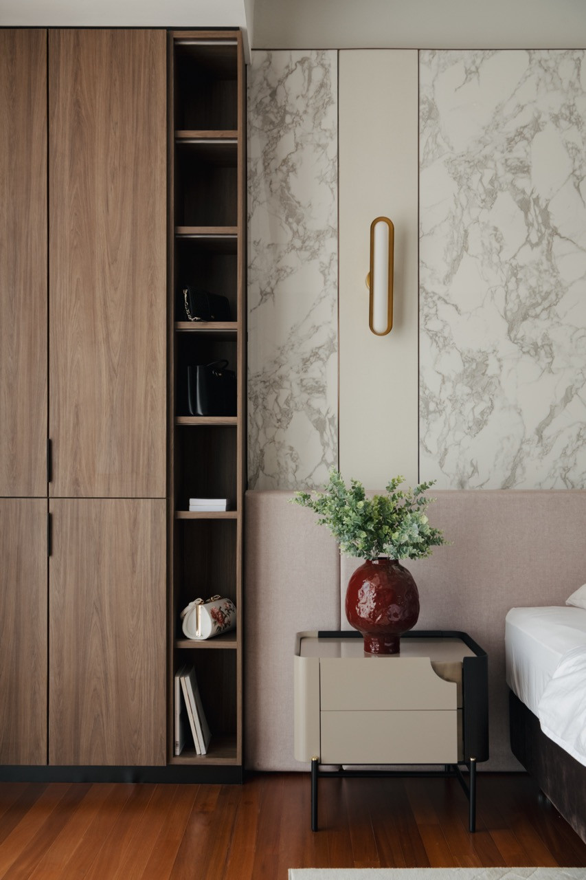 Floor-to-ceiling storage cabinets feature book-matched marble doors with bronze hardware, creating a sophisticated backdrop for the contemporary bedroom furniture