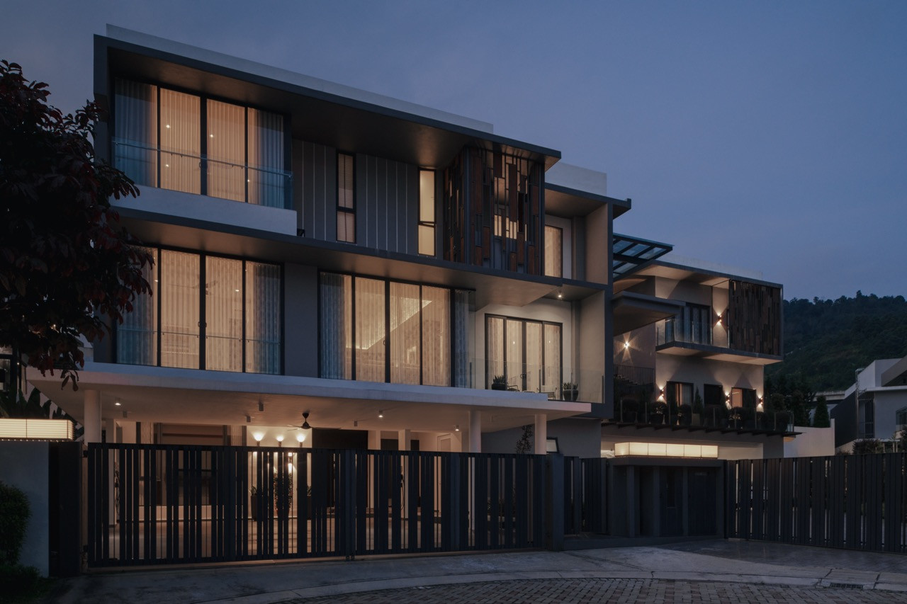 The evening exterior reveals how the expanded compound addresses contemporary Malaysian family living while respecting the suburban bungalow typology