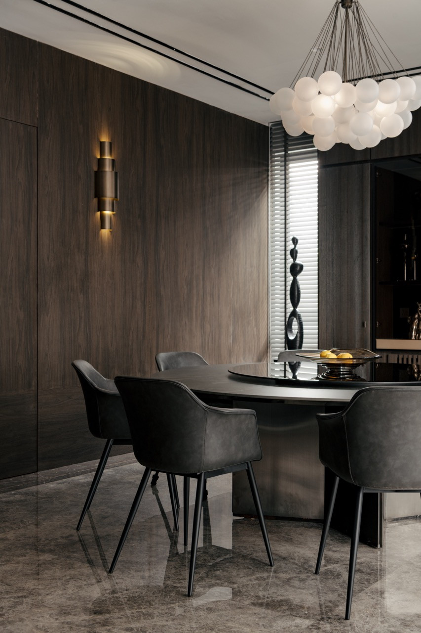 Custom walnut millwork frames the formal dining area, where bronze accent lighting highlights the textured wall surface