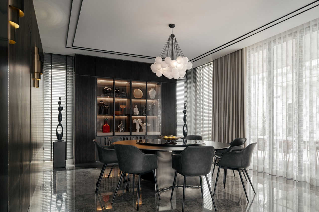 The formal dining room’s sculptural lighting installation creates a dramatic focal point visible from the double-volume living area