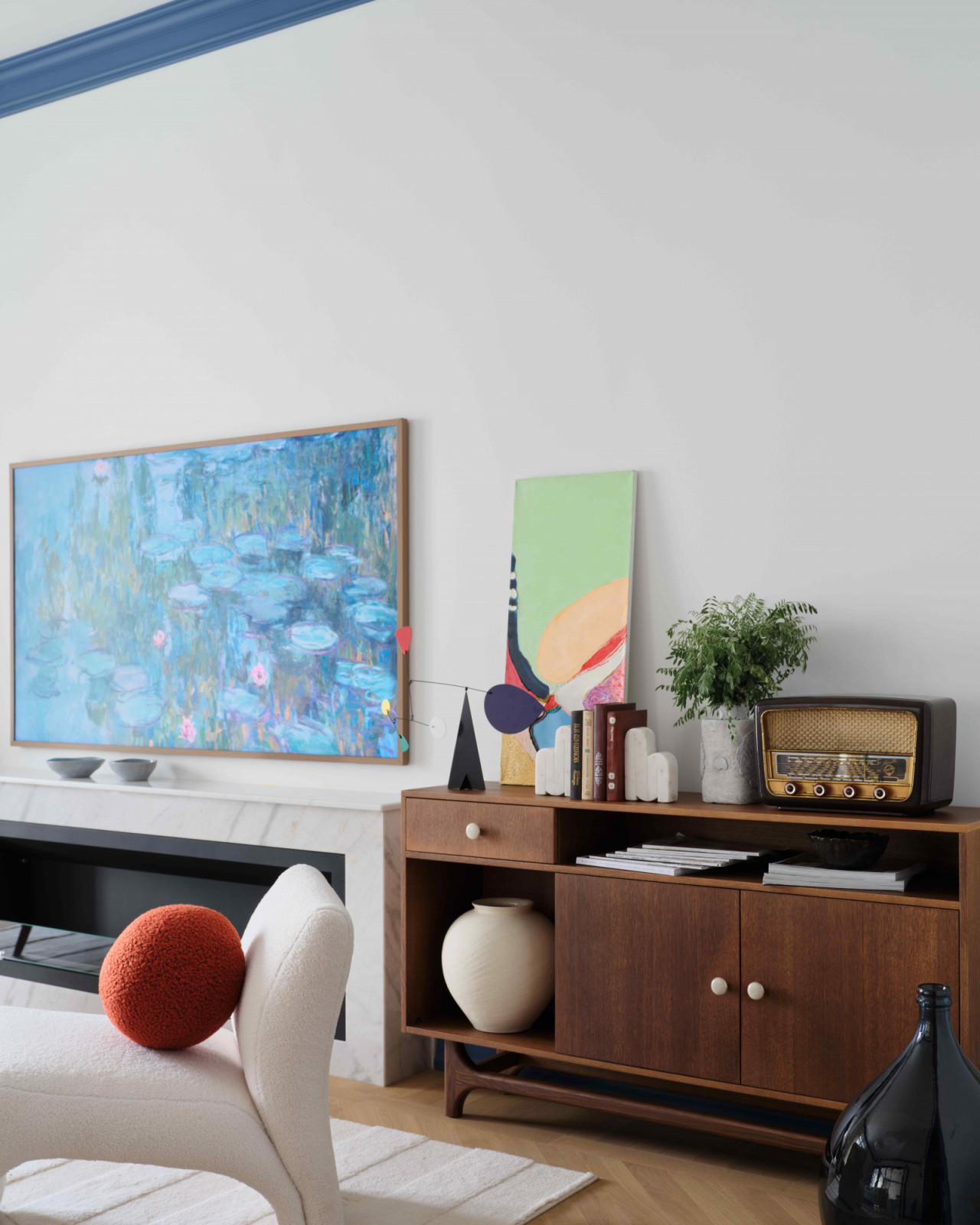 A vintage 1960s radio atop a wooden cabinet sits next to the marble biofuel fireplace