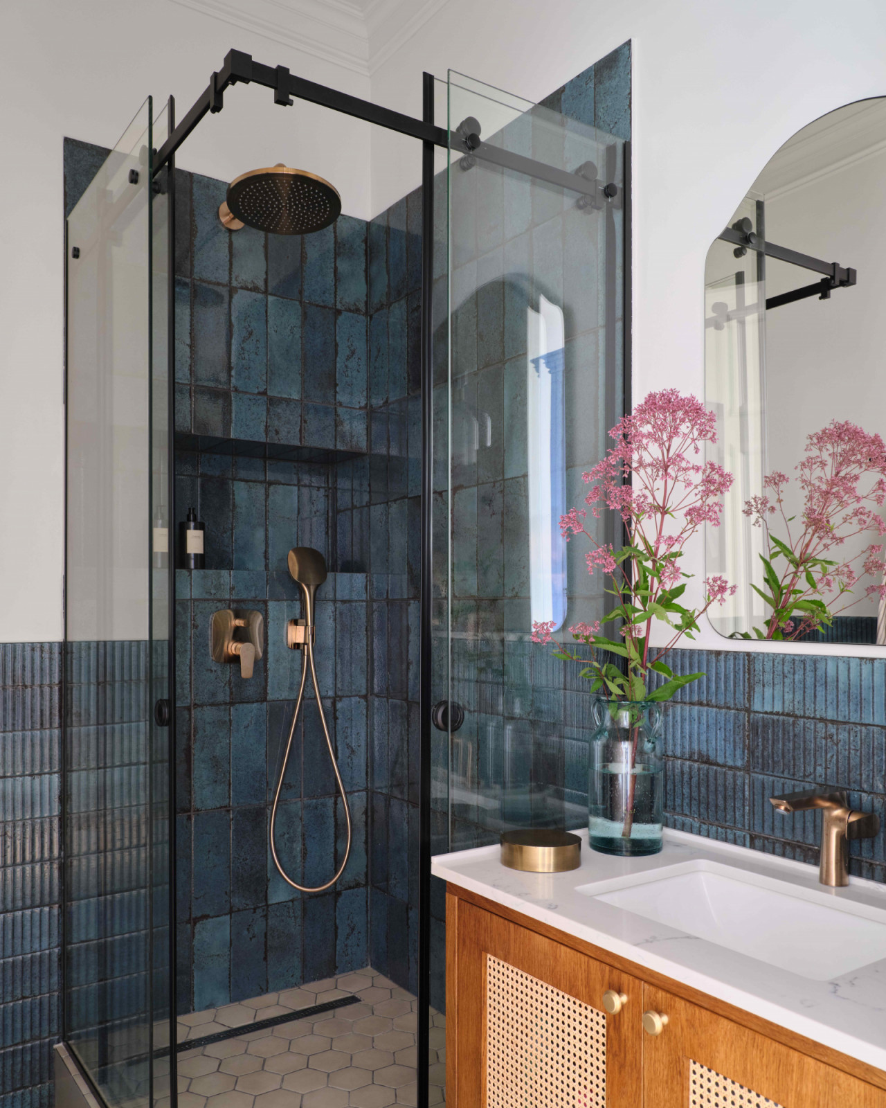 The guest bathroom with gilded fixtures against the dark tile walls