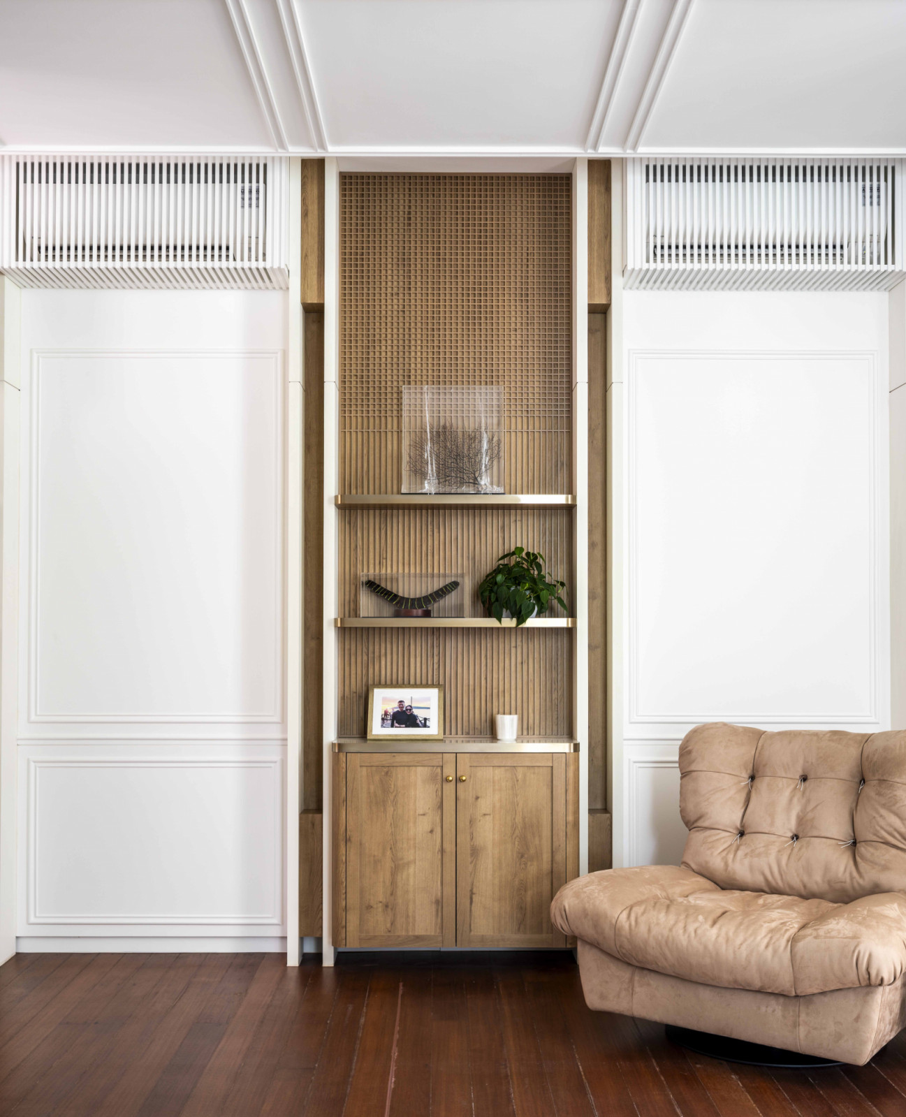 A cosy seating corner sits beside a wall niche with display shelves, offering a quiet spot for rest and reflection